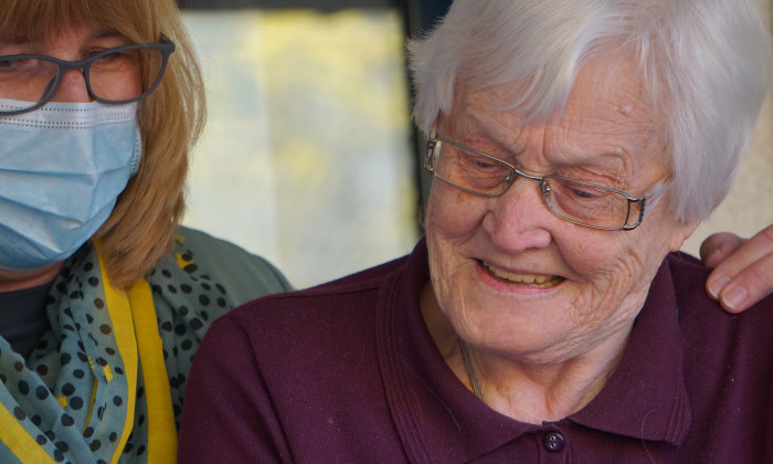 Caregiver with arm over the shoulder of senior citizen
